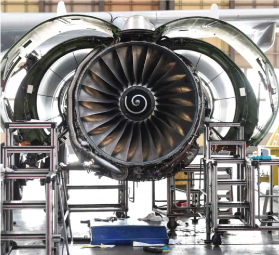 Jet engine with visible fan blades mounted on testing rig inside industrial facility.